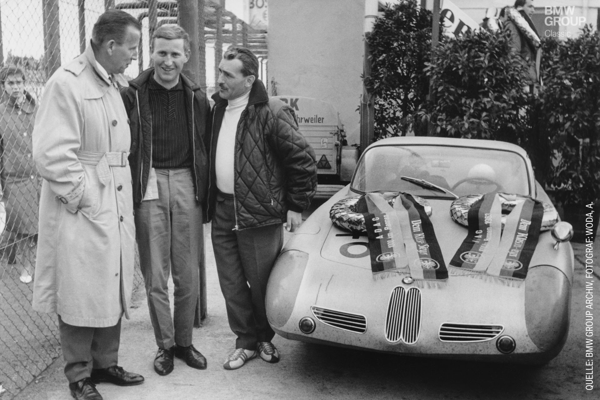 Drei Männer stehen neben einem BMW 700