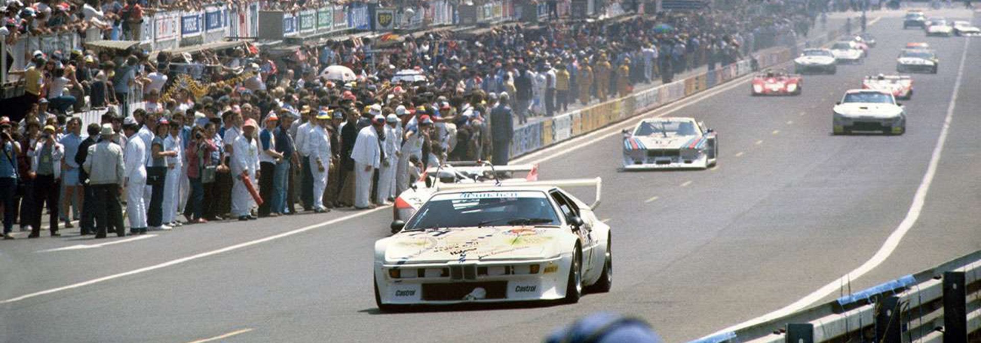 BMW M1 racing car during the race at the 24 Hours of Le Mans, surrounded by other vehicles on the track.